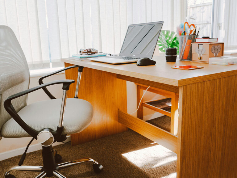 A small office featuring an office chair, desk, laptop and other office supplies